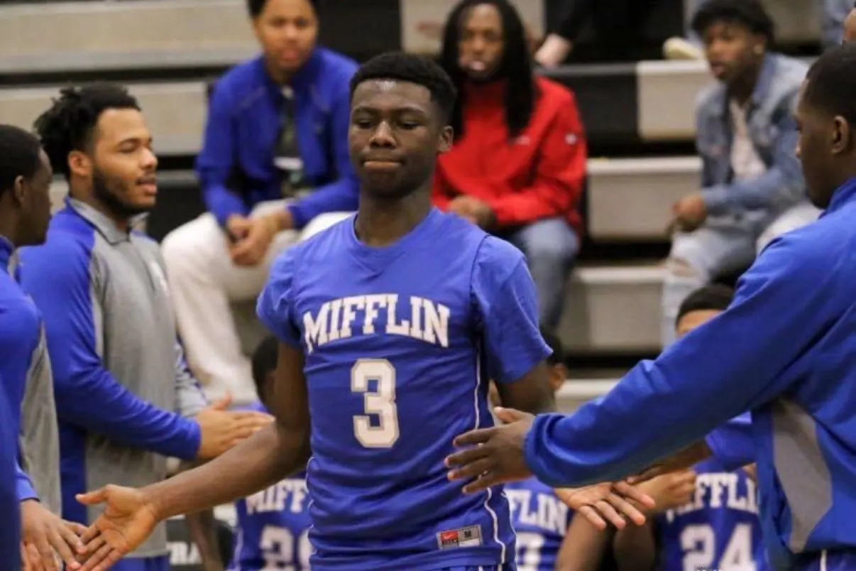 High-school basketball players high-fiving a team-mate during pre-game introductions.