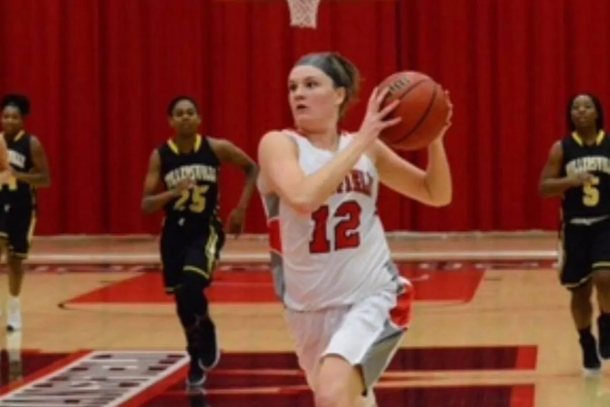A high-school girls&rsquo; basketball player driving to the basket in a number 12 jersey.